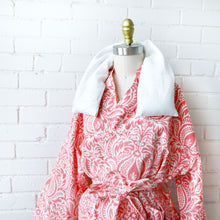 Load image into Gallery viewer, Red and white patterned robe with therapy wrap on a mannequin against a white brick wall.