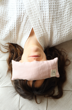 Load image into Gallery viewer, Person lying down with a pink eye pillow on a light surface