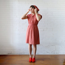 Load image into Gallery viewer, Woman wearing a red dress and red shoes against a white brick wall.