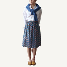 Load image into Gallery viewer, Person wearing a white shirt, blue patterned skirt, and blue scarf on a white background