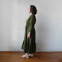 Load image into Gallery viewer, Woman wearing a green dress standing against a white brick wall.