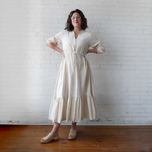 Load image into Gallery viewer, Woman wearing a white dress standing against a white brick wall.