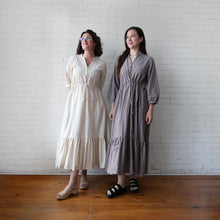 Load image into Gallery viewer, Two women standing side by side against a white brick wall, wearing long dresses.