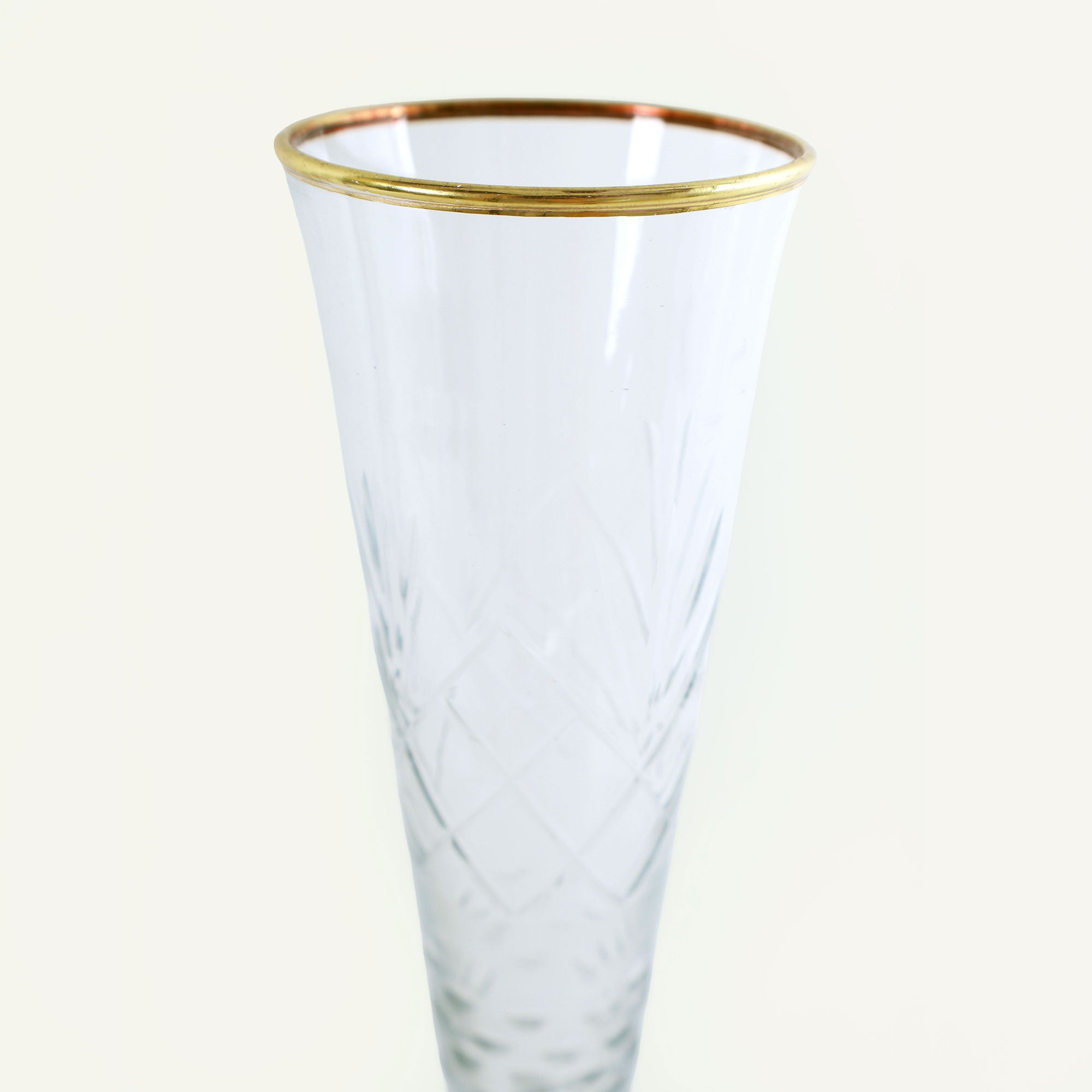 Clear glass flute with gold rim on a white background