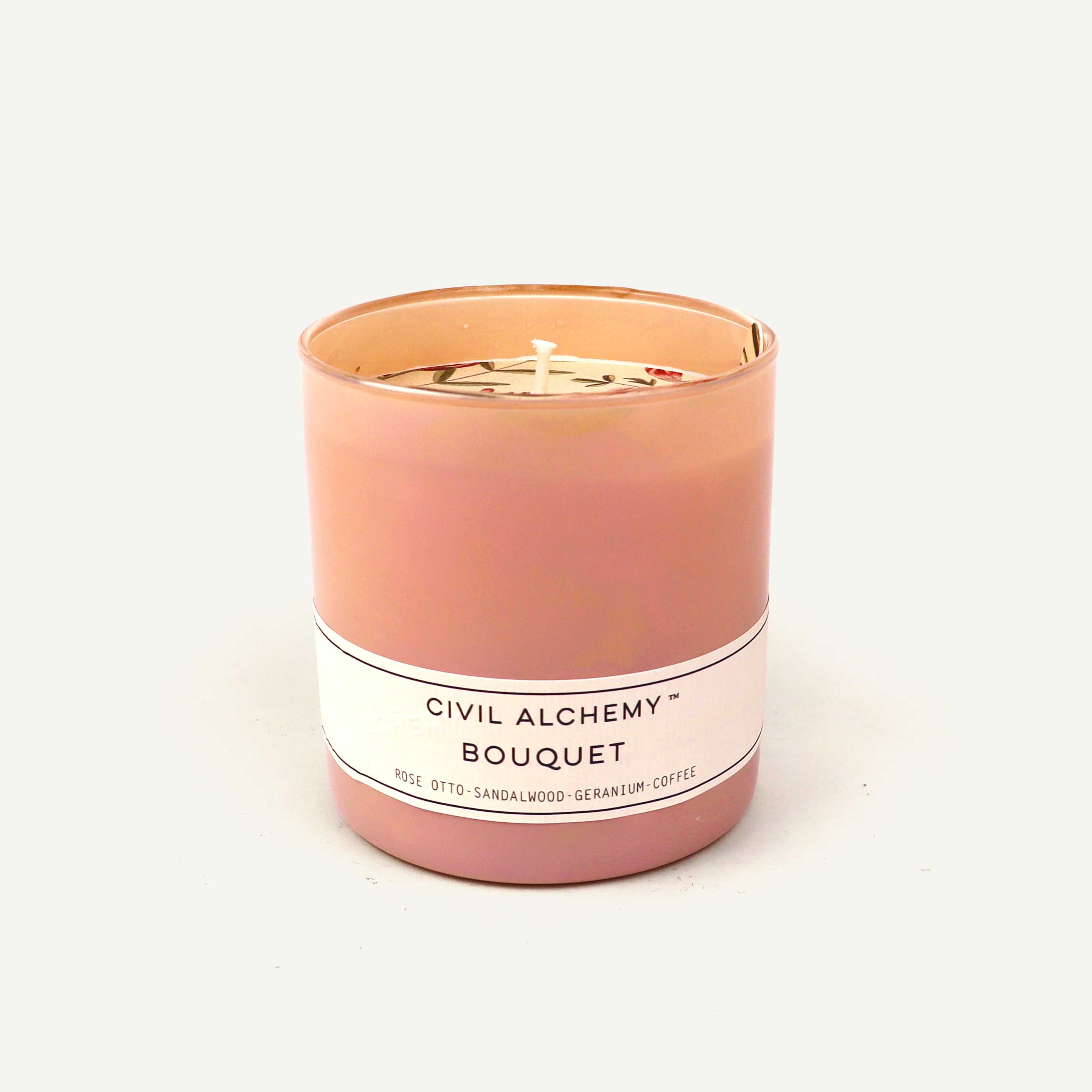 Pink candle with a white label on a light beige background