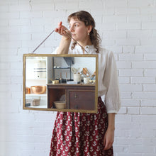 Load image into Gallery viewer, Woman holding a rectangular mirror with a wooden frame against a white brick wall.

