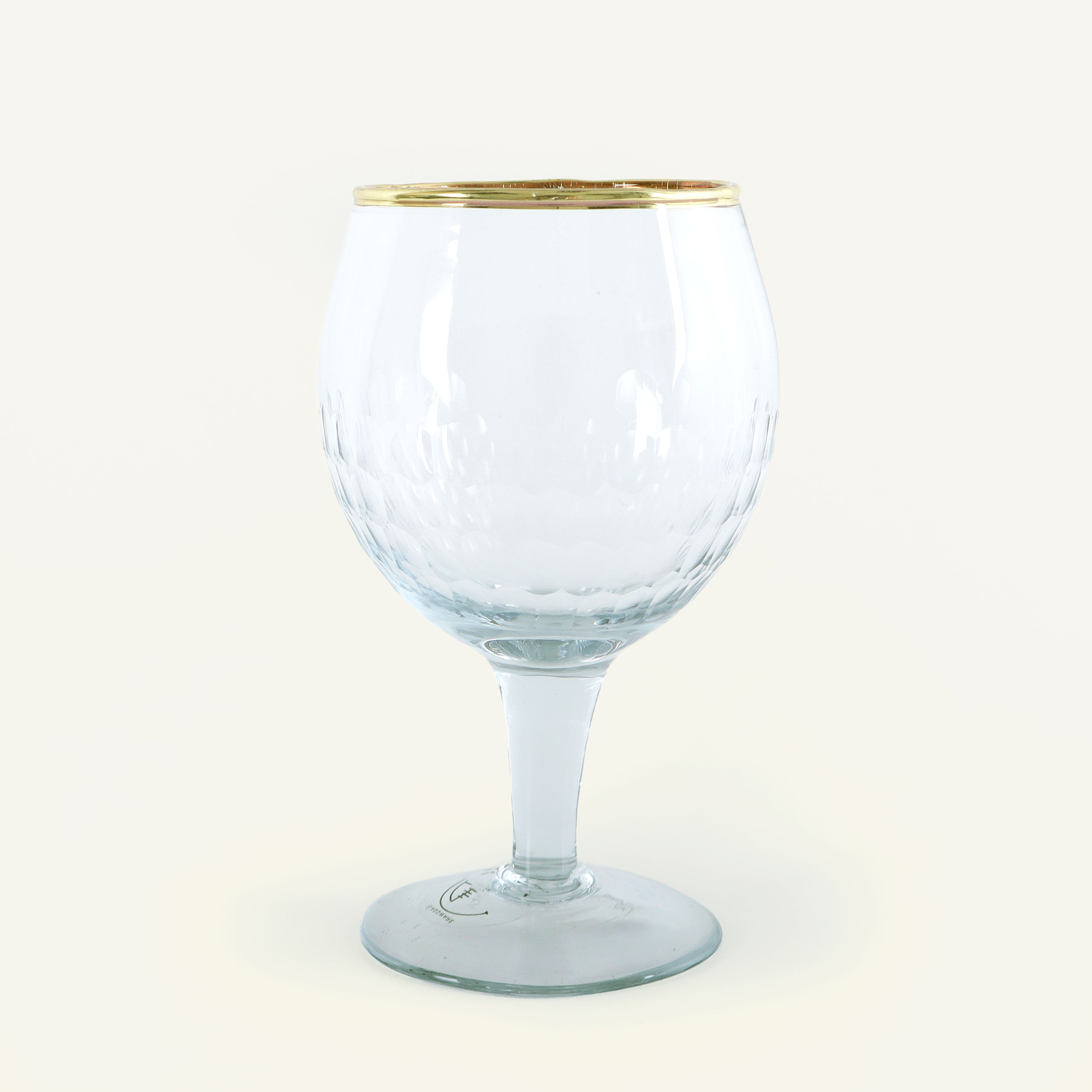Clear glass goblet with gold rim on a white background