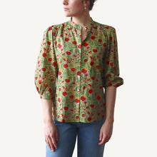 Load image into Gallery viewer, Woman wearing a green floral blouse with red flowers on a white background
