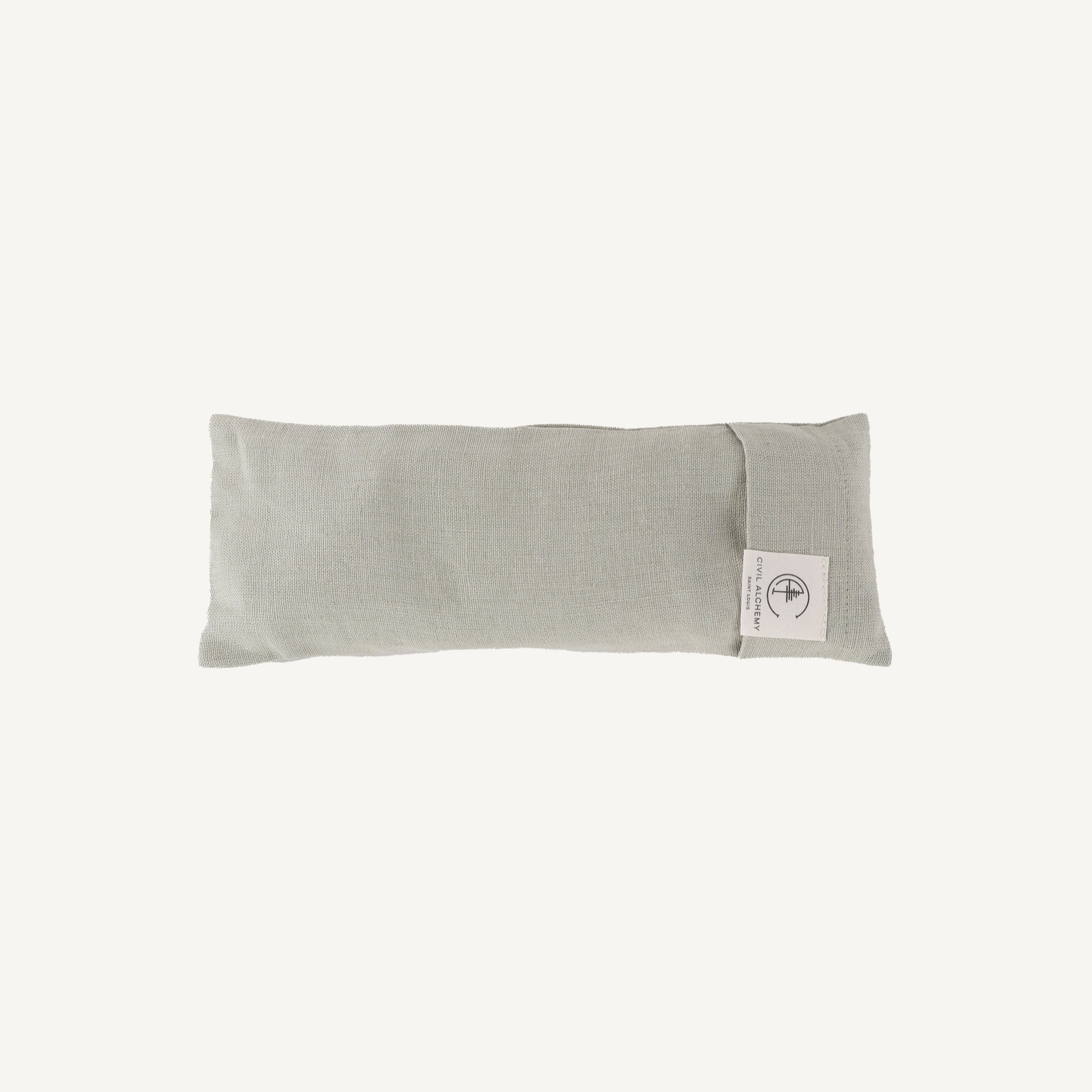 Green eye pillow with a brand label on a white background