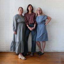 Load image into Gallery viewer, Three women posing together against a white brick wall.
