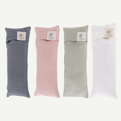 Four fabric eye pillows in blue, pink, green, and white on a white background.