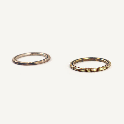 Two gold rings with textured band design on a white background